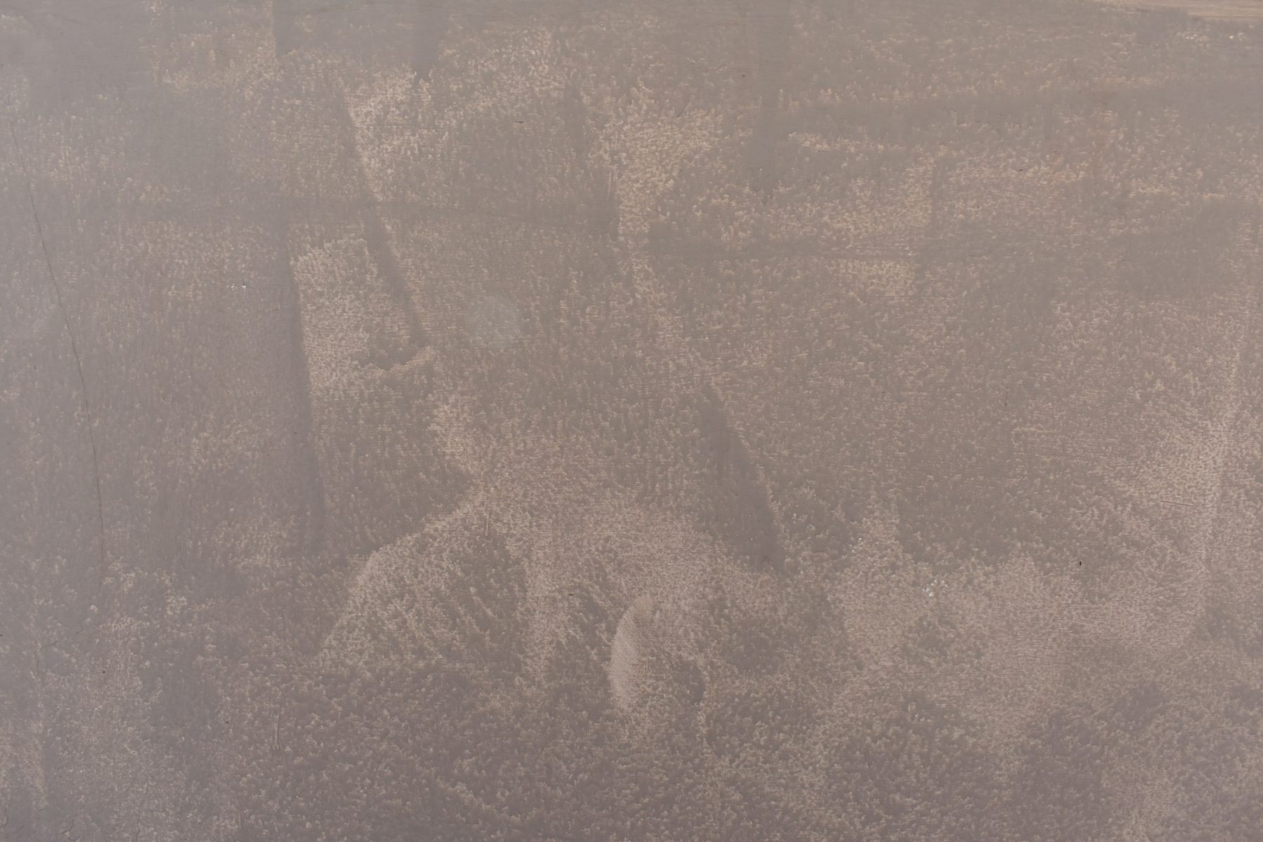 Close-up van een gladgestreken minerale afwerking in een taupe tint met lichte wolking.