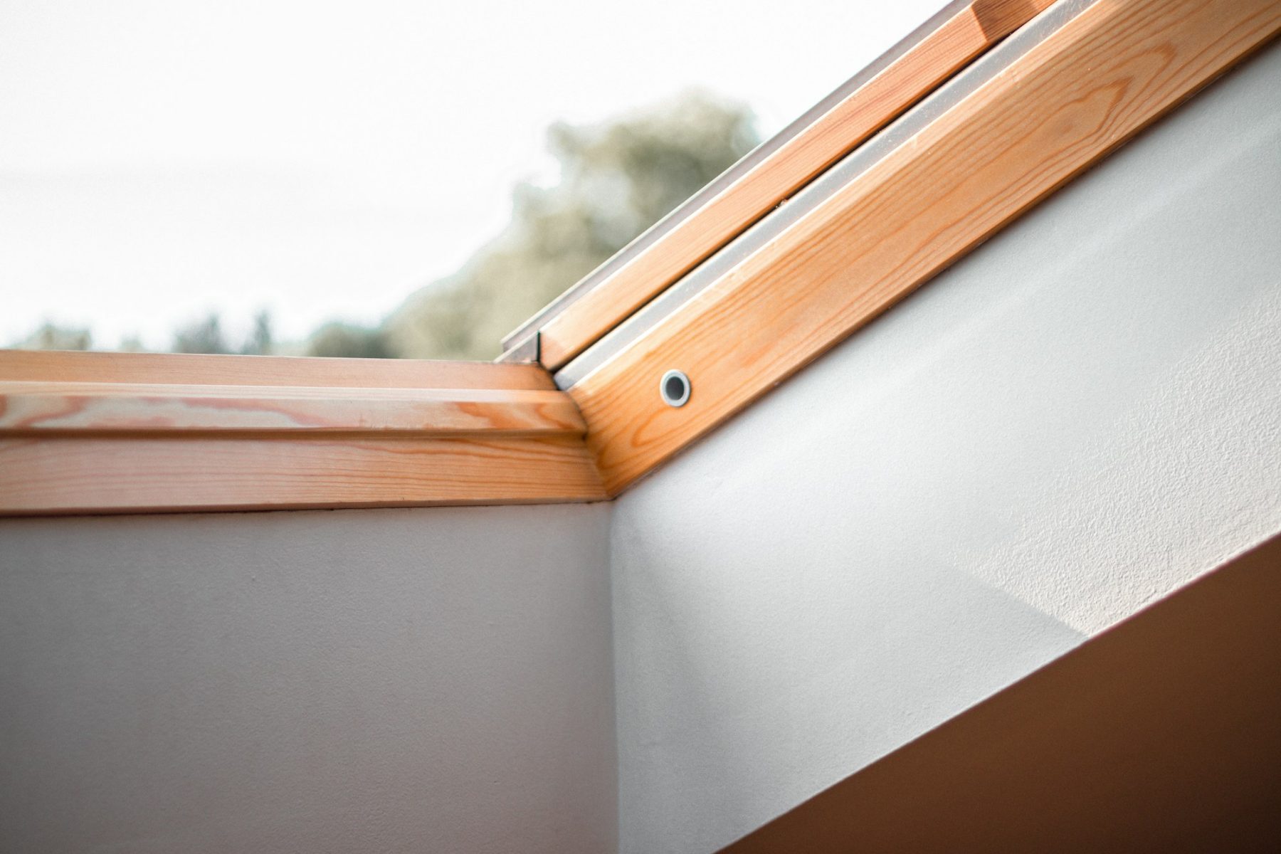 Detail van de aansluiting tussen een houten dakraamkozijn en het stucwerk.
