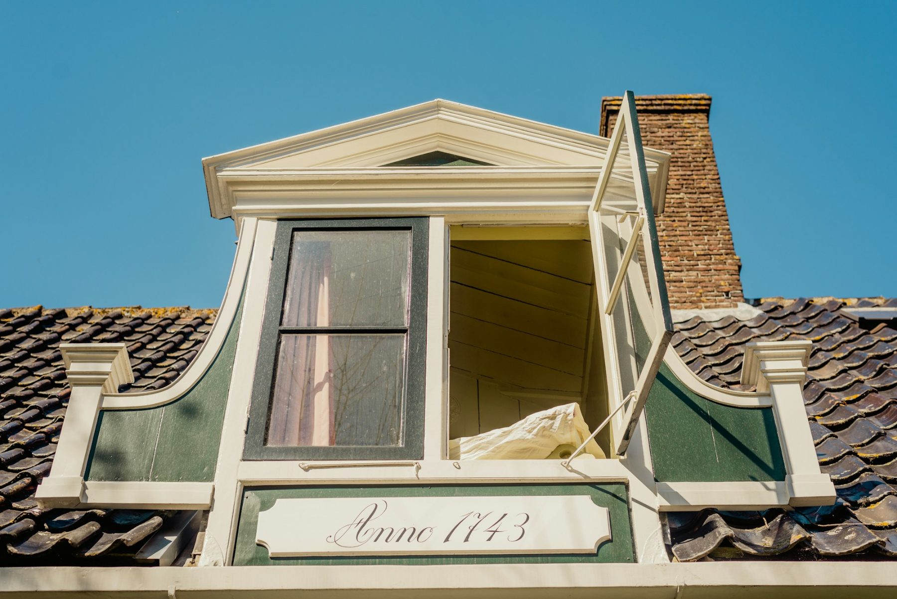 Historische Zaanse dakkapel met groen-crème afgewerkt houtwerk uit Anno 1743