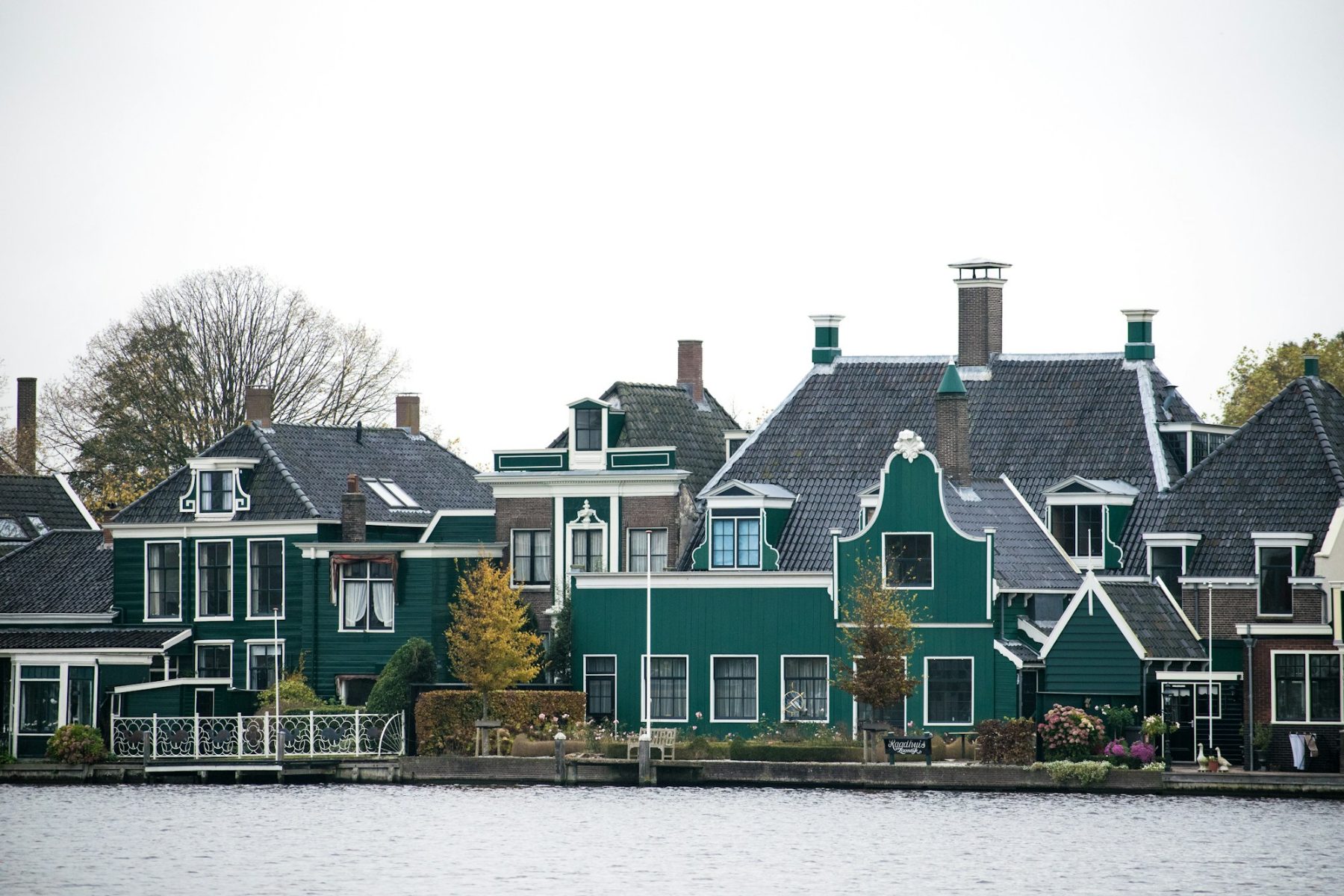 Karakteristieke donkergroene Zaanse huizen met strak wit geschilderd houtwerk aan het water